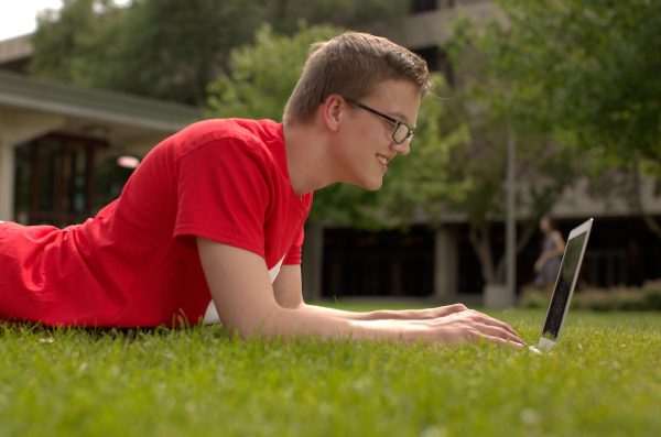 Student on laptop outside on grass
