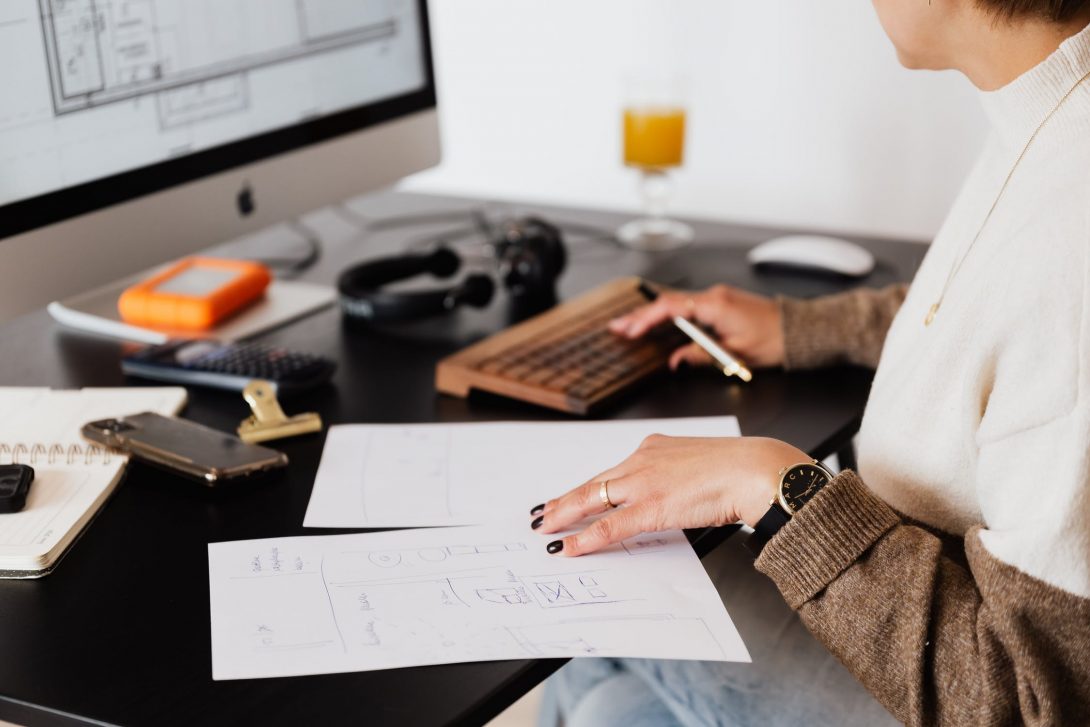 Woman on computer with pen and paper