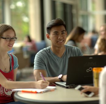 UIC students sitting at table with laptop conversing
                  