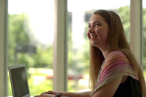 Female student smiling while using laptop
