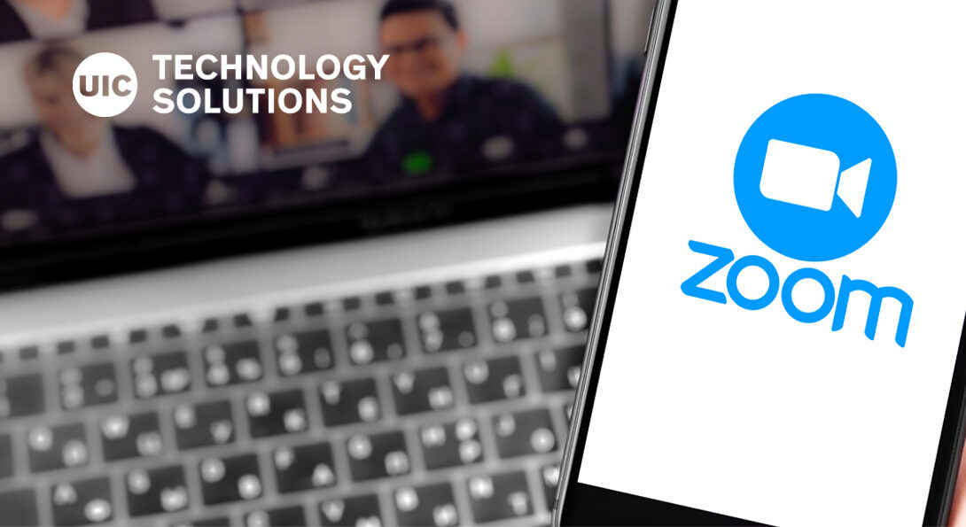 Zoom logo on a smartphone with a laptop in the background