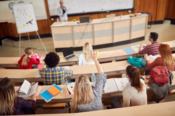 student raising hand in lecture hall