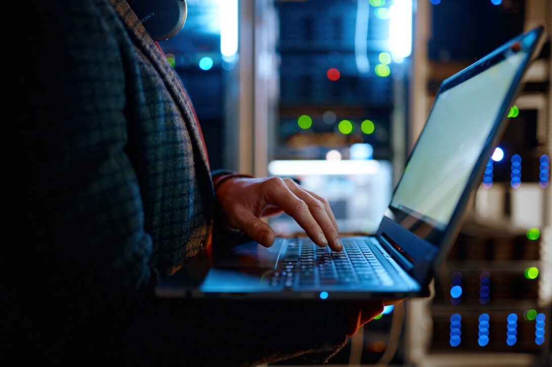 Man using laptop in server room