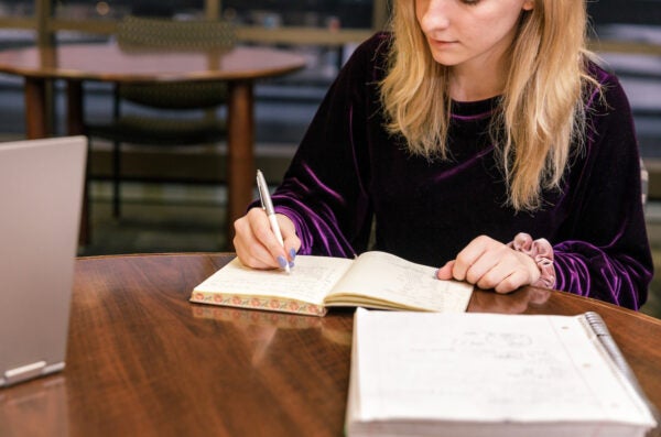 individual making notes in a notebook