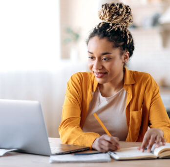 A student using a laptop and taking notes
                  